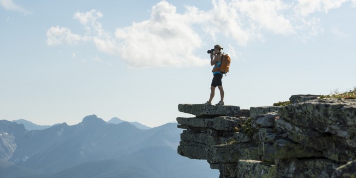 Hiker takes picture from bluff above mountains